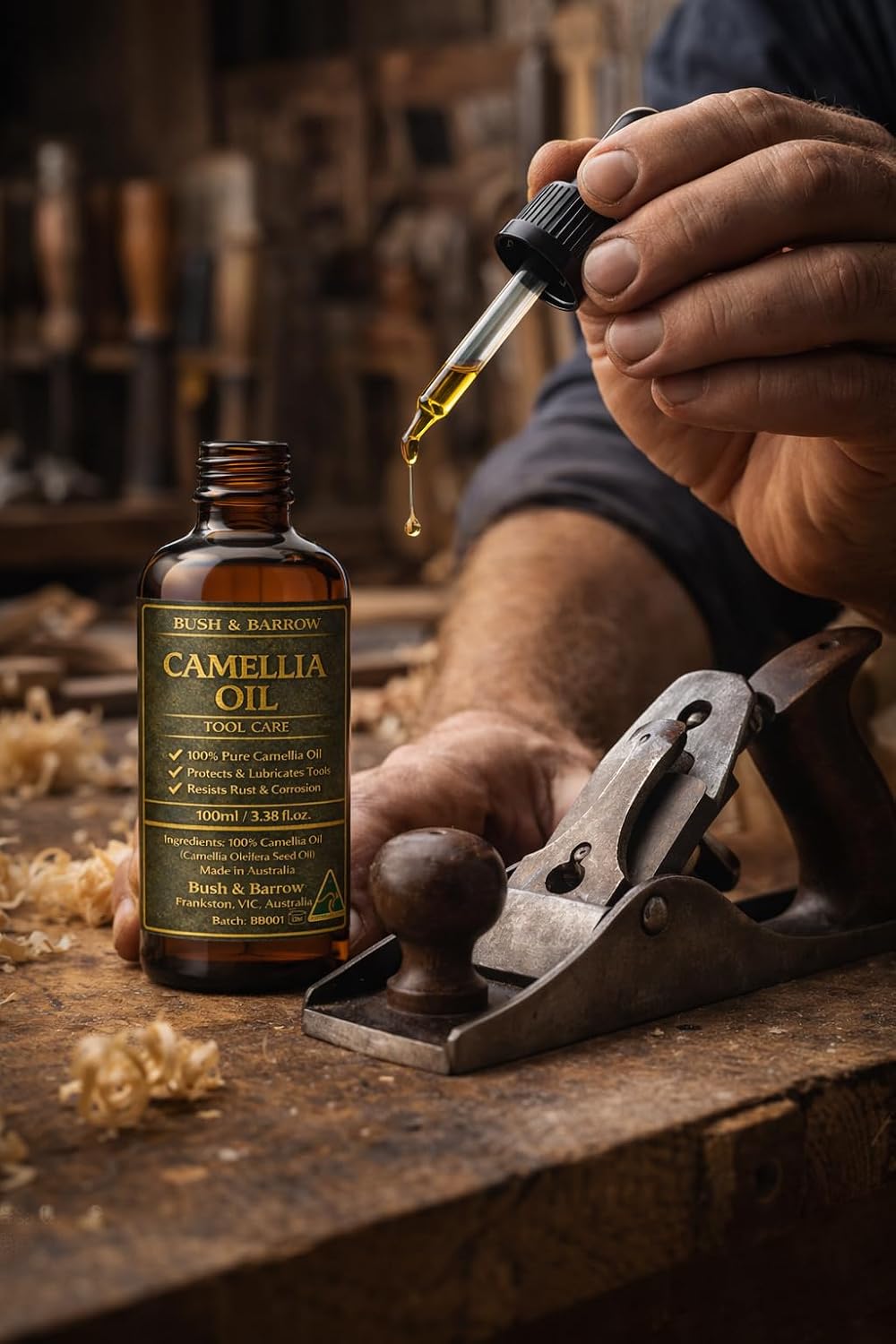 Camellia Oil being dropped from a glass pipette beside a hand plane on a workshop bench with wood shavings
